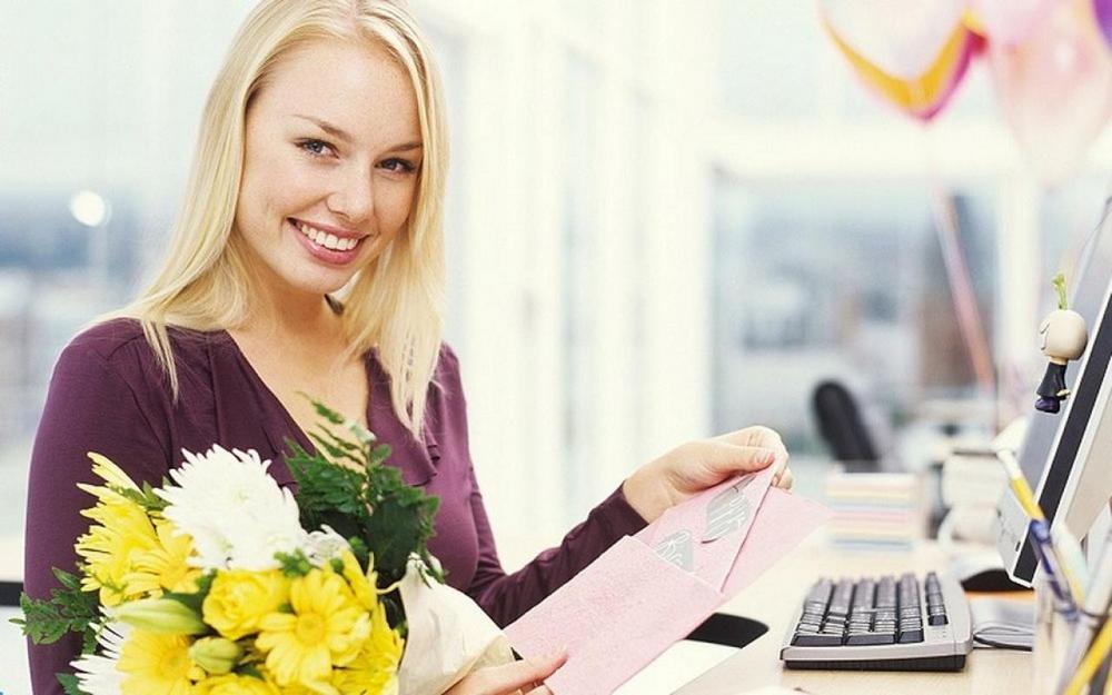 Девушка с цветами за рабочим столом