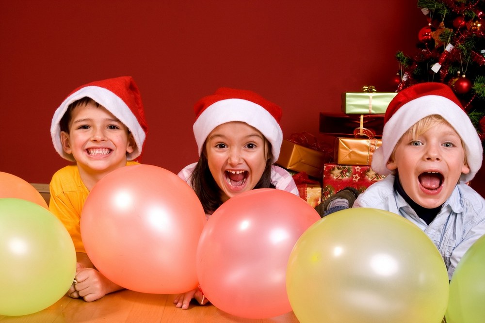 Дети в новогодних колпаках возле шаров