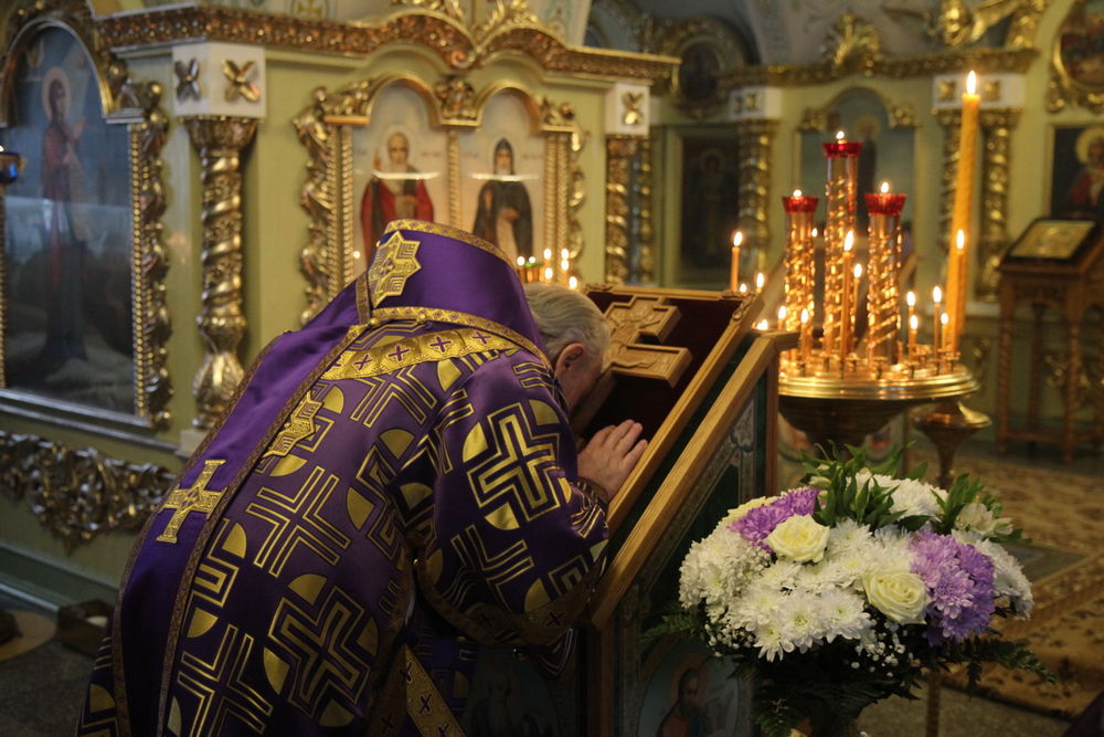 Священник над крестом, свечи в церкви