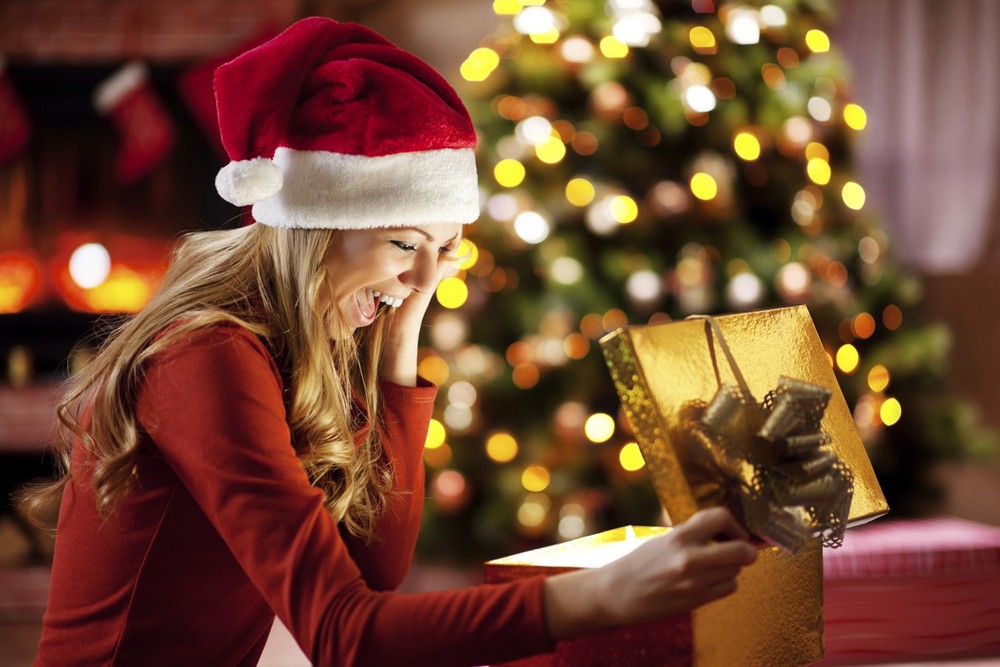 Девушка с подарочной коробкой на фоне новогодней елки