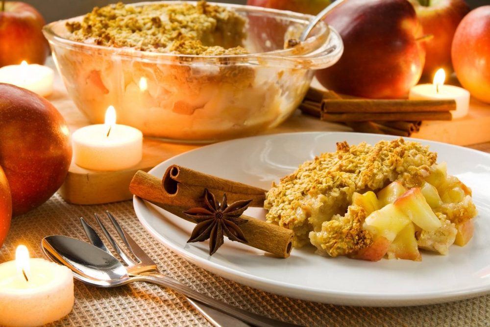 Блюдо на тарелке, свечи, яблоки, столовые приборы на столе