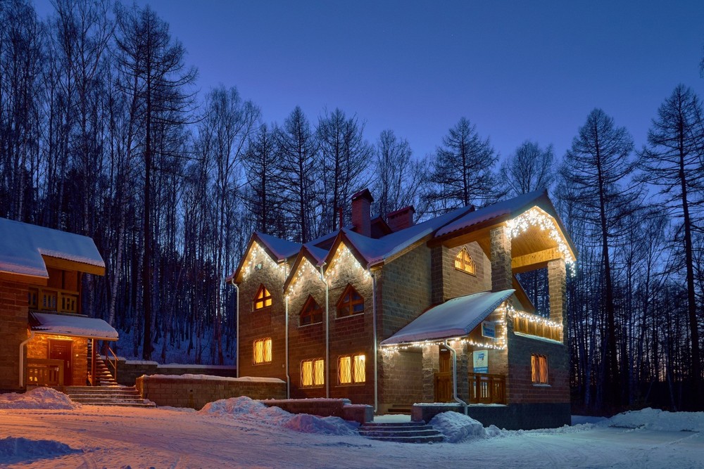 Дома, украшенные гирляндами, деревья, снег