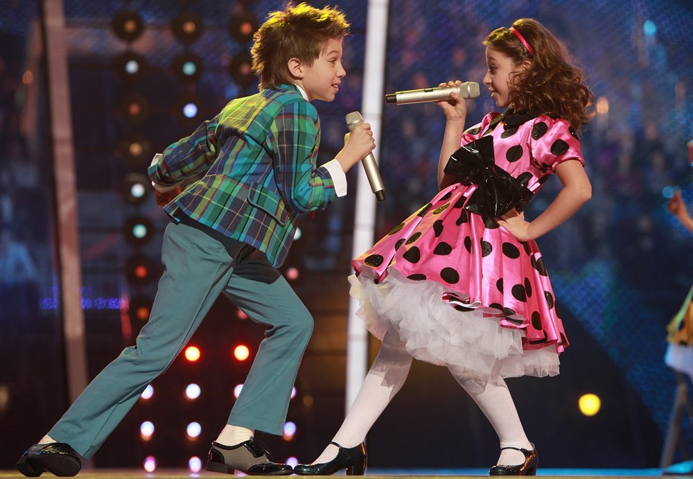 Мальчик и девочка с микрофонами на сцене