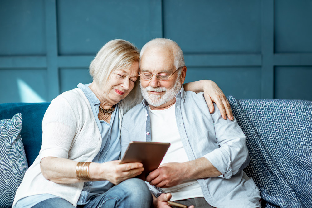 Пожилые мужчина и женщина на диване с планшетом