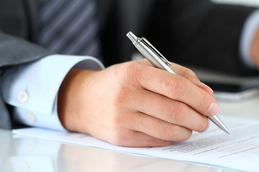 Ручка в руке и документ на столе