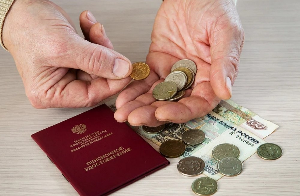 Деньги возле пенсионного удостоверения и монеты в руках